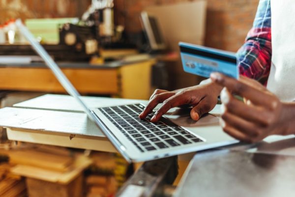 Carpenter at work shopping online using laptop computer and credit card